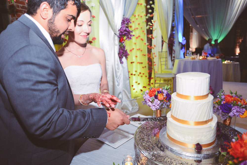 A wedding couple cut their wedding cake at the Foundry at Puritan Mill