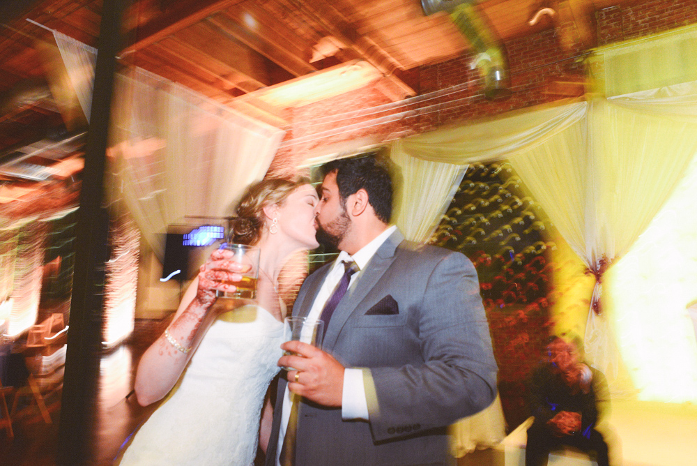 A wedding couple kiss during their wedding reception at the Foundry at Puritan Mill