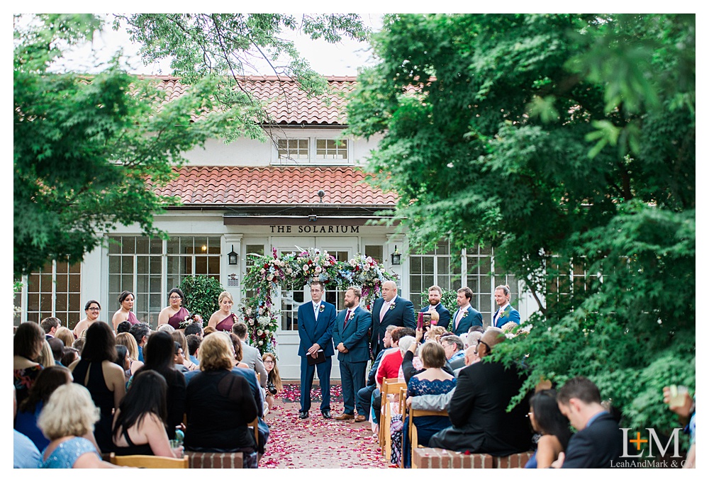 A groom stands at the altar waiting for his bride with all the people from their wedding guest list